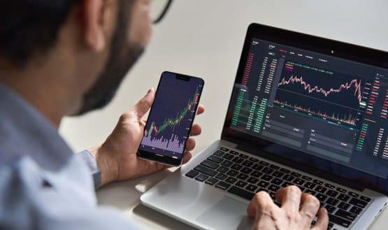 Man trading on laptop and phone