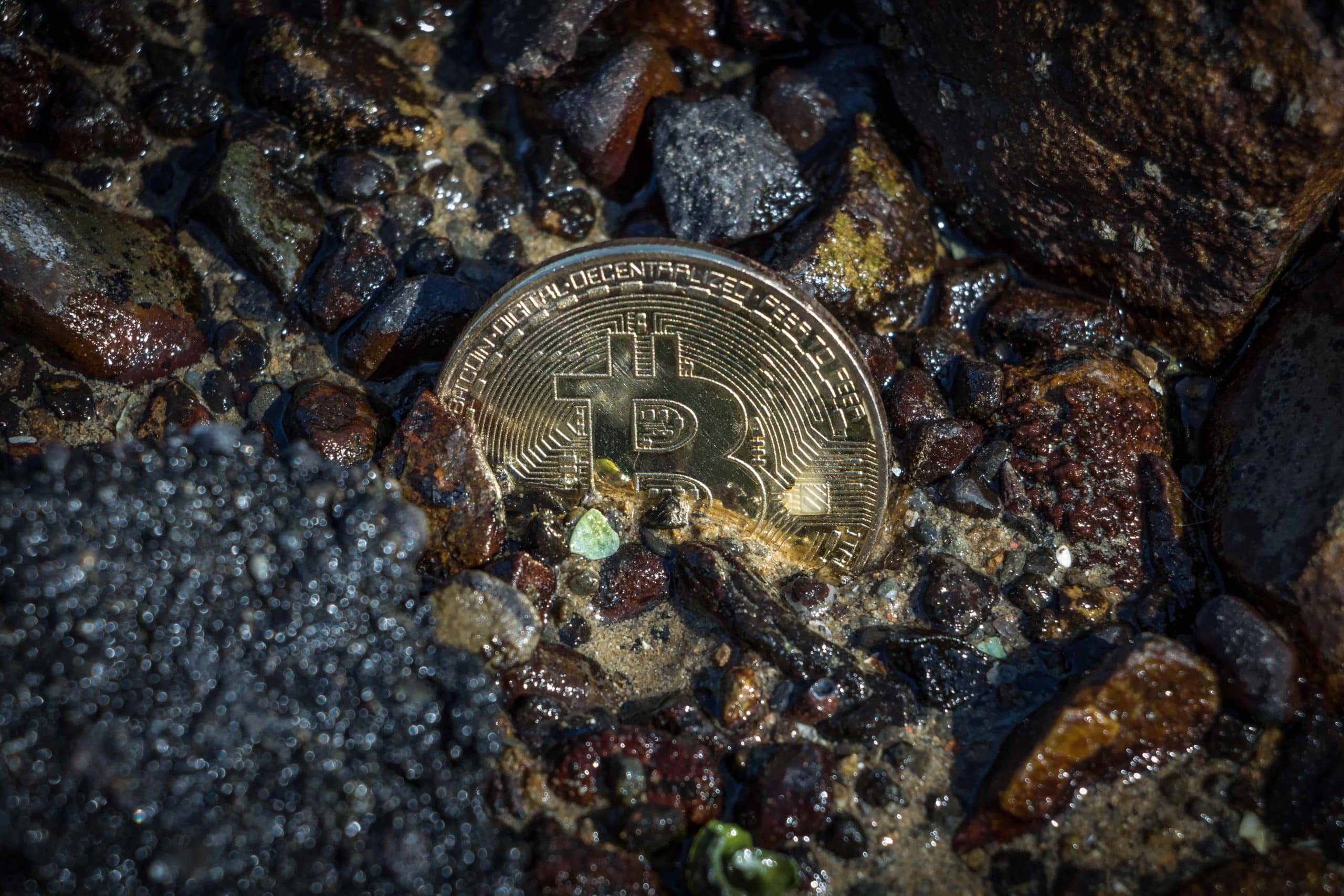 How much Bitcoin has been lost forever? Image shows partially buried Bitcoin under rocks